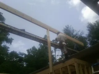 Carpenter setting a ridge beam over a new addition frame — Ice Dam Removal by Roofing Brothers in Bogota