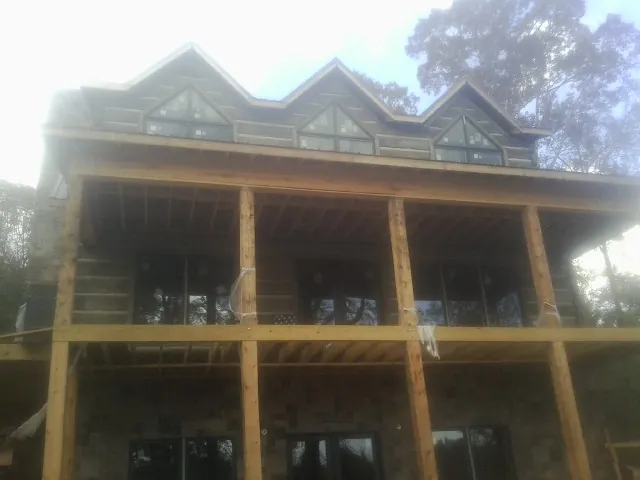 Dormers and porch framing on a large log home under construction — Roof Coating work by our crew in Bogota