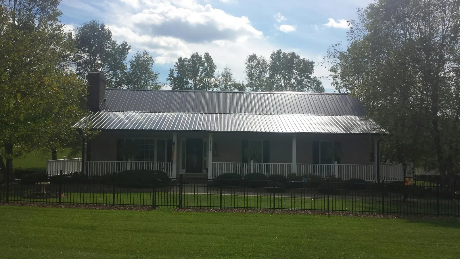Gray metal roof on a brick ranch with a full width front porch — Gutter Guard Installation work by our crew in Bogota
