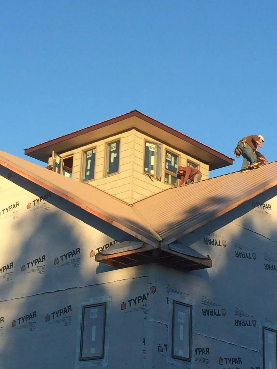 Roofers working around a rooftop cupola on a new metal roof at sunset — Roof Waterproofing in Bogota by Roofing Brothers